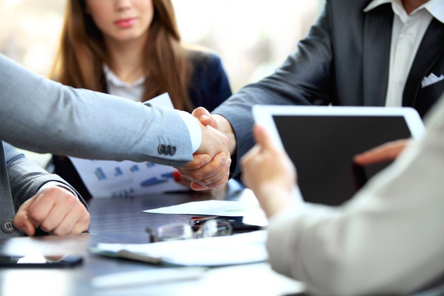 Professionals shaking hands over a meeting table